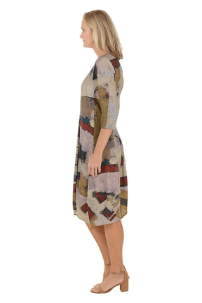 A woman wearing a 3/4 sleeve brown dress with a red and green multi colored pattern. Side shot.