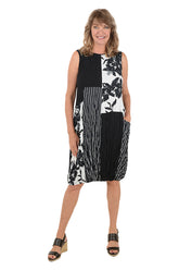 Woman wearing a black and white sleeveless dress with a pocket on the left side and an asymmetrical hem.