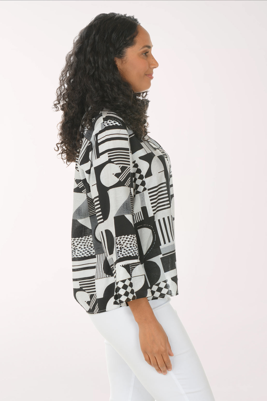 Woman wearing a black and white geometric patterned shirt against a white background