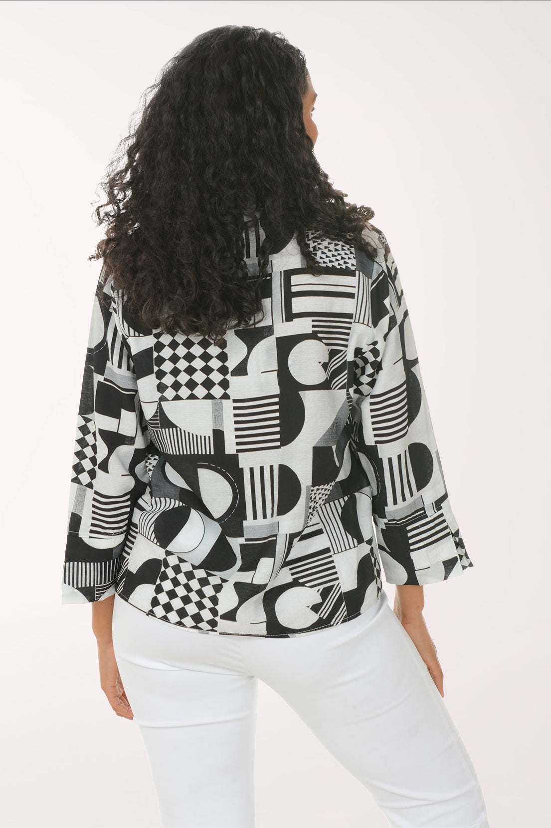 Woman wearing a black and white geometric patterned shirt against a white background