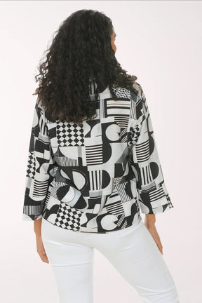 Woman wearing a black and white geometric patterned shirt against a white background