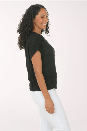 Woman wearing a black t-shirt and white pants on a white background