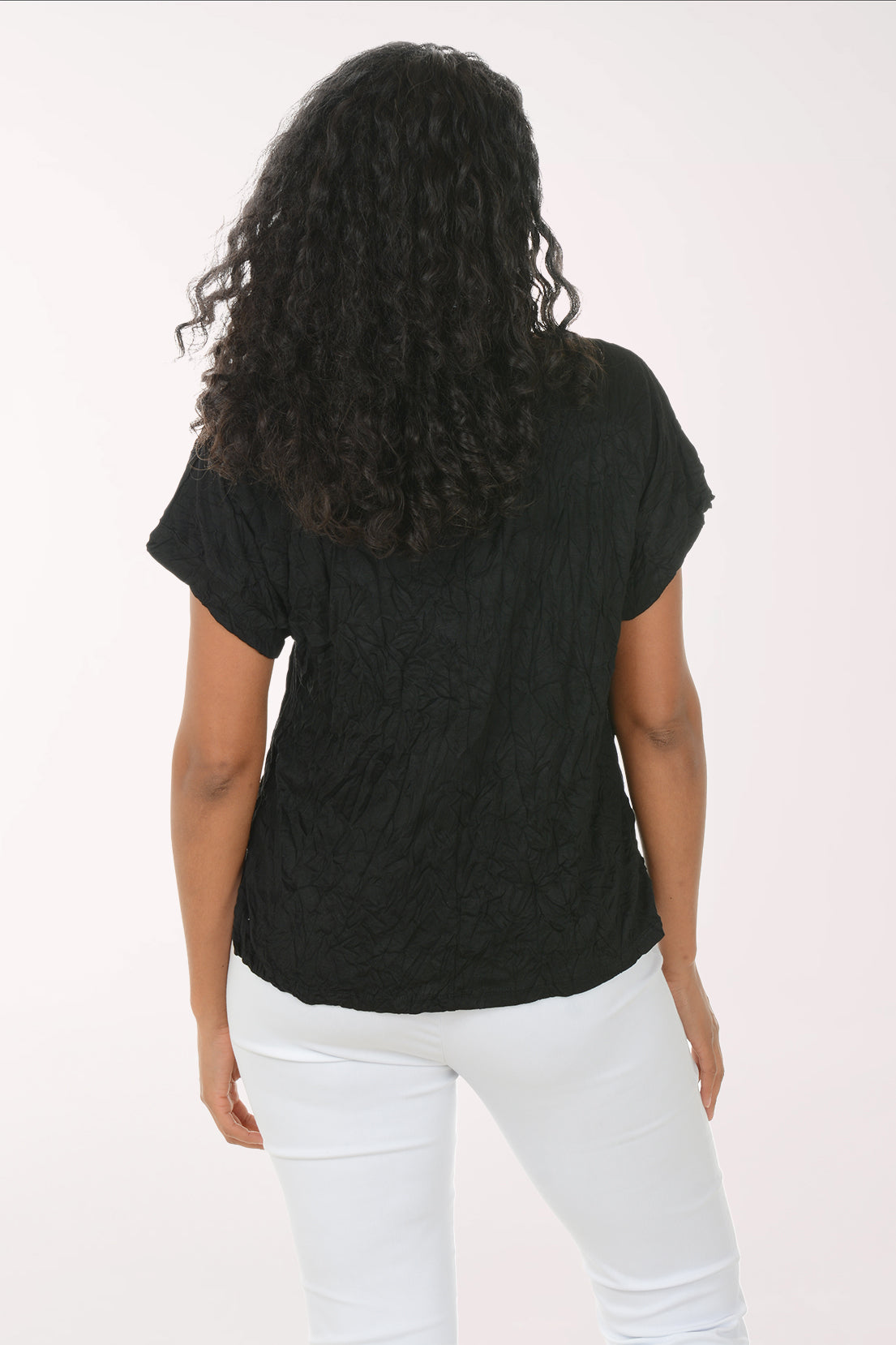 Woman wearing a black t-shirt and white pants on a white background