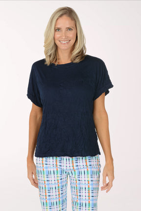 Woman wearing a navy blue top and plaid pants on a white background