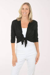 Woman wearing a black cardigan over a white top and pants on a white background