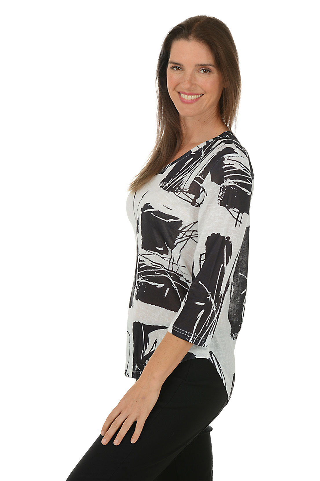 Woman wearing a black and white abstract patterned top on a white background. Side shot.