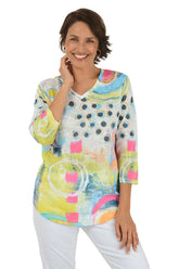 Woman wearing a colorful abstract patterned top on a white background.