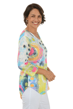 Woman wearing a colorful abstract patterned top on a white background. Side shot.