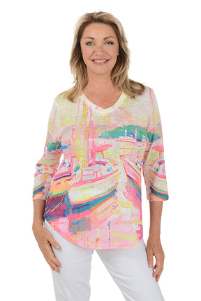 A woman wearing a multi-colored 3/4 sleeve v-neck top with a boat watercolor pattern.