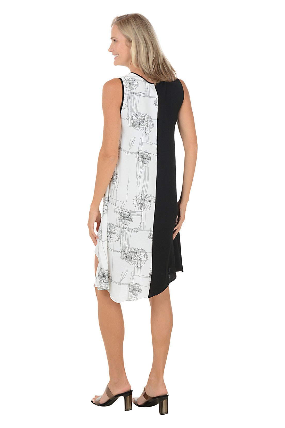 Woman wearing a black and white sleeveless dress with a large pocket on the left side and an asymmetrical hem. Back shot.