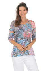 Woman wearing a colorful patterned top on a white background.