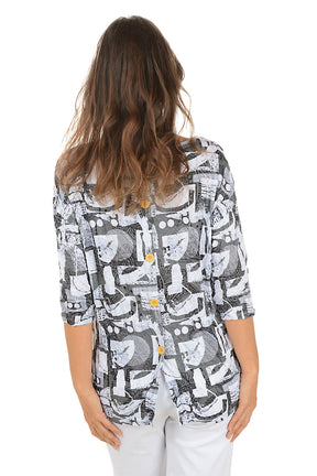 Woman wearing a grey geometric patterned top and white pants on a white background. Back shot.