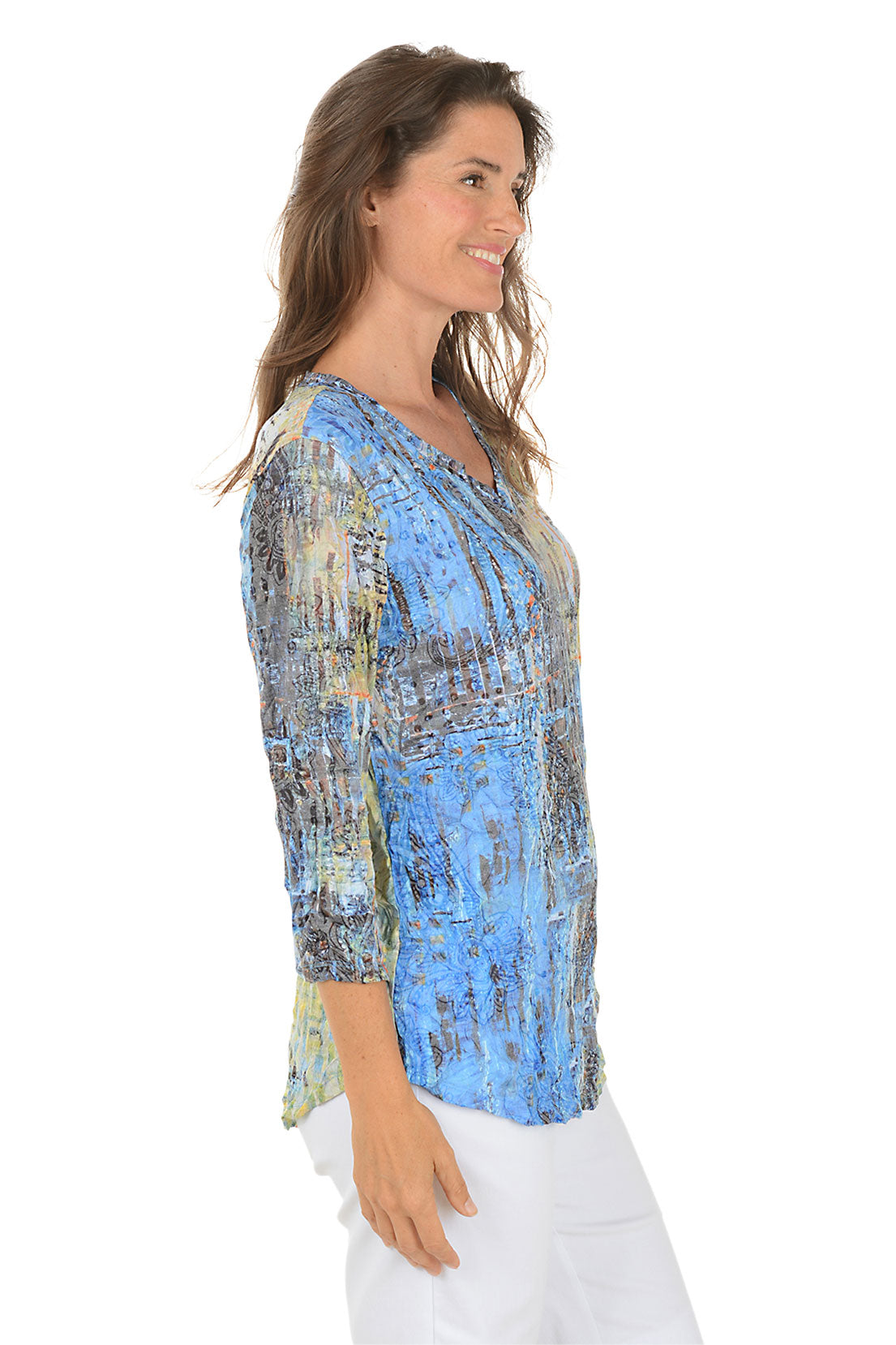 Woman wearing a colorful abstract patterned top on a white background. Side shot.