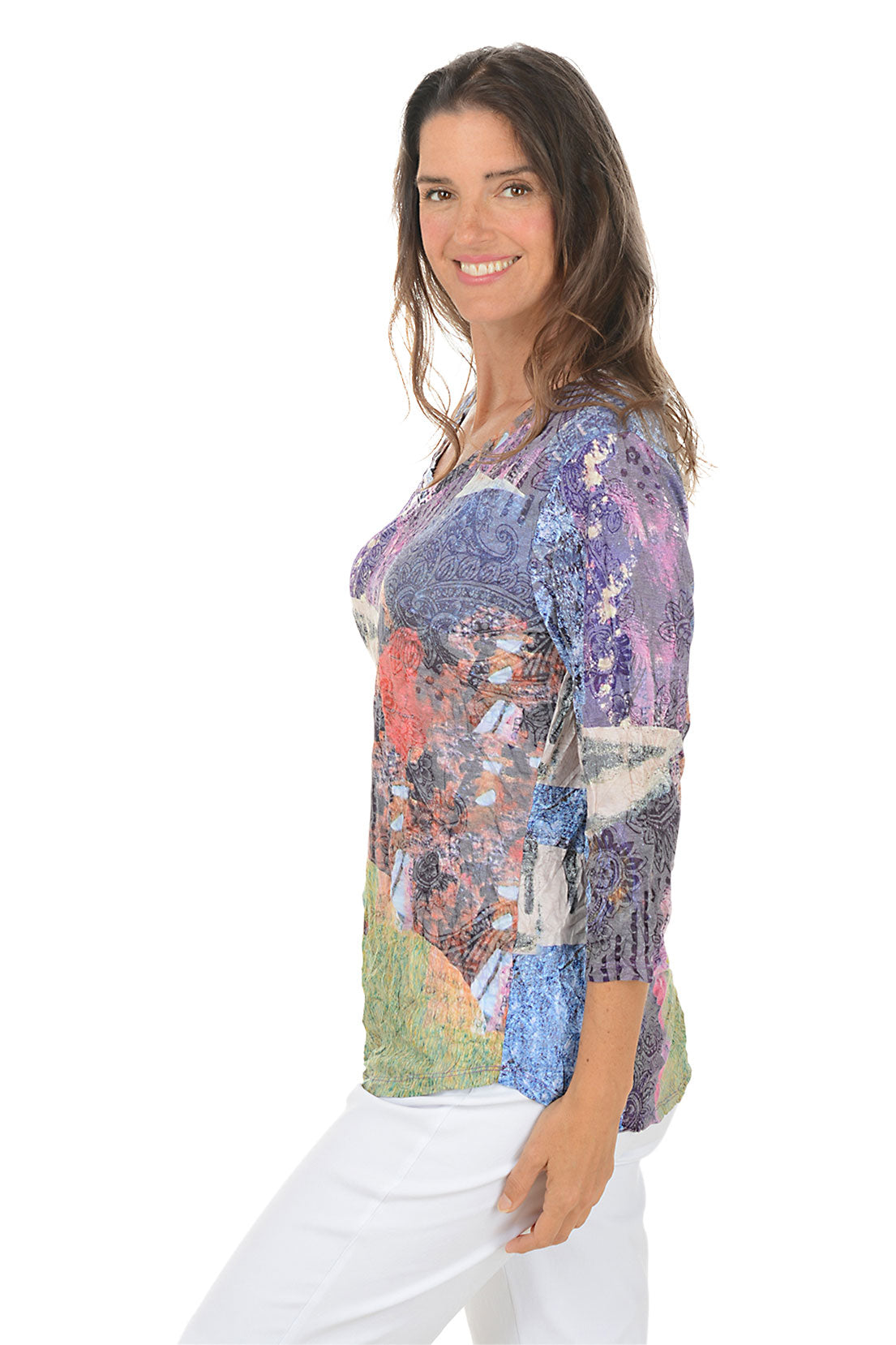 Woman wearing a 3/4 sleeve colorful hemline patterned blouse with a white background. Side shot.