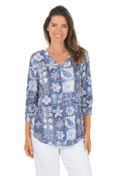 Woman wearing a blue floral patterned blouse on a white background.