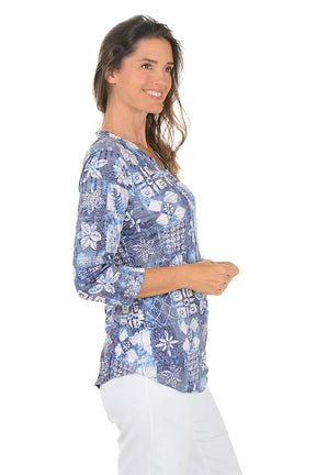 Woman wearing a blue floral patterned blouse on a white background. Side shot.