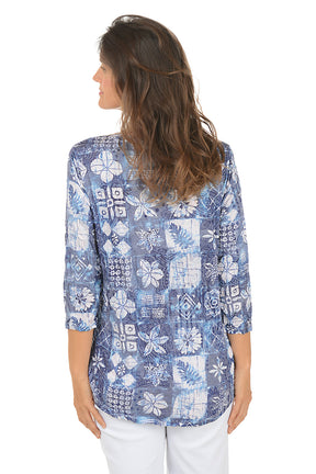 Woman wearing a blue floral patterned blouse on a white background. Back shot.
