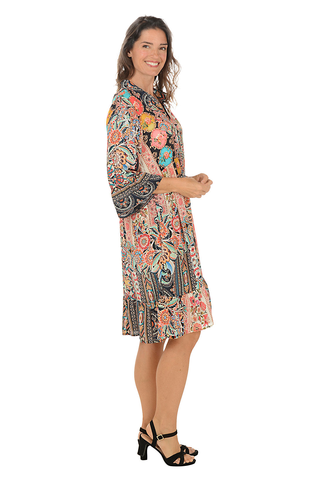 Woman wearing a colorful patterned dress on a white background. Side shot.