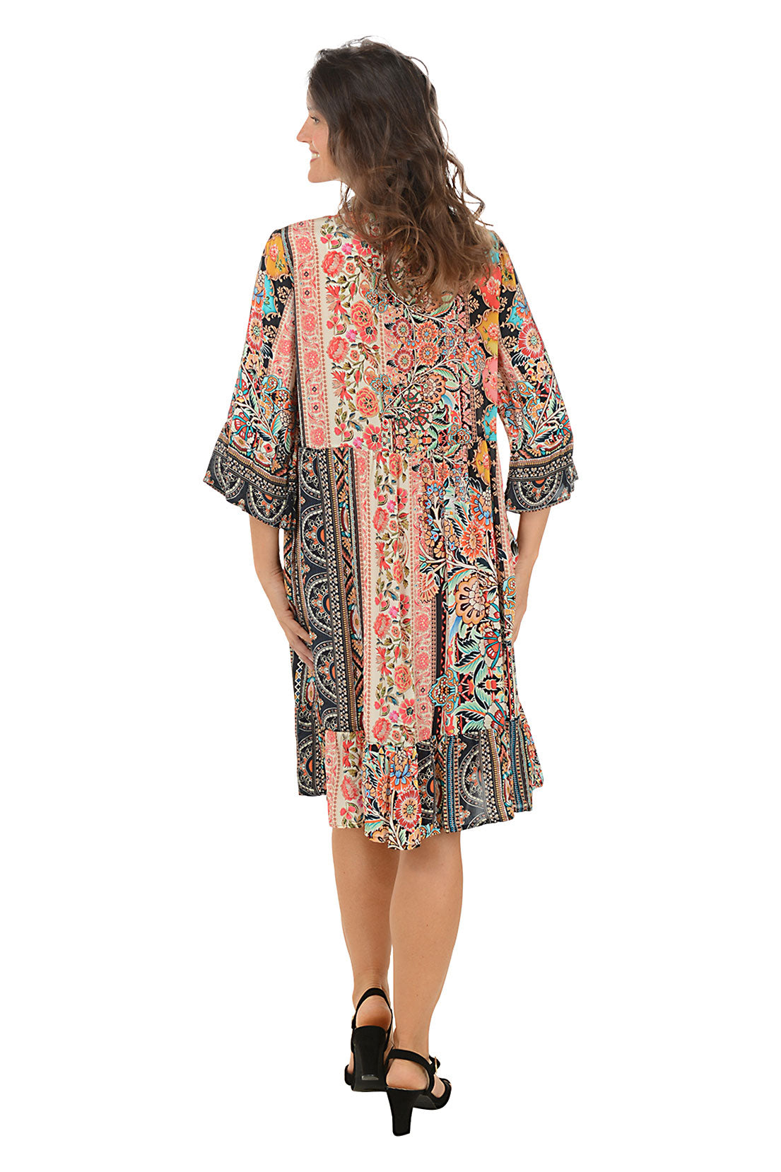 Woman wearing a colorful patterned dress on a white background. Back shot.
