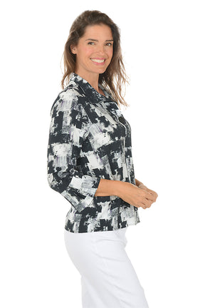 Woman wearing a patterned blouse and white pants on a white background. Side shot.