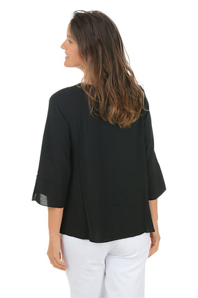 Woman wearing a black blouse with sheer sleeves on a white background. Back shot.