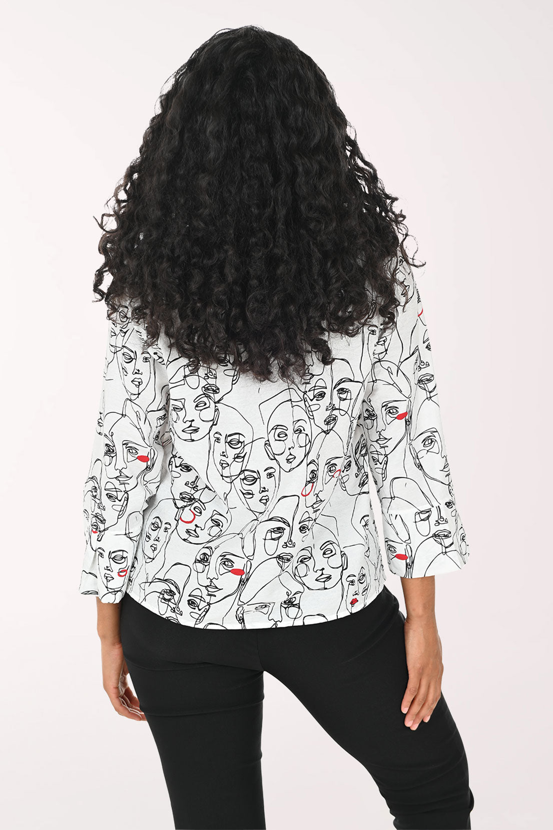 Woman wearing a white blouse with black line art design on a white background