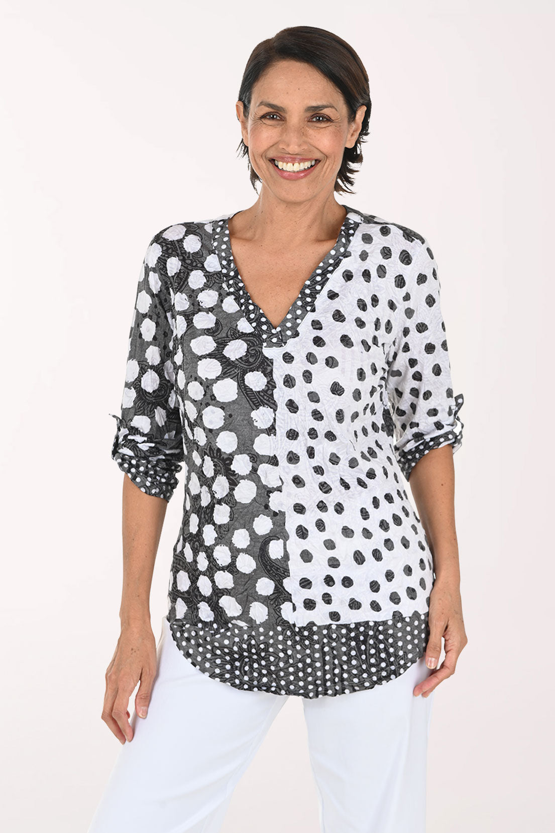 Woman wearing a 3/4 sleeve v-neck black and white polka dot top