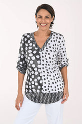 Woman wearing a 3/4 sleeve v-neck black and white polka dot top