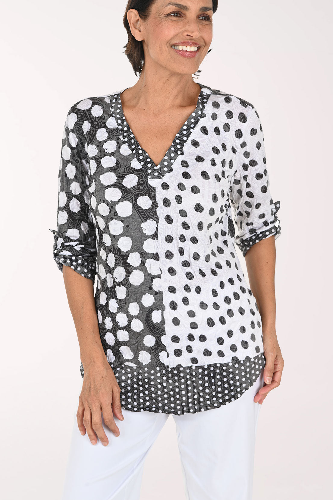 Woman wearing a 3/4 sleeve v-neck black and white polka dot top