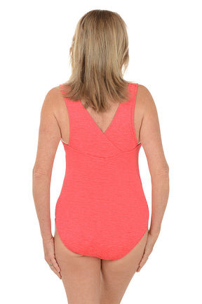 Woman wearing a coral pink swimsuit on a white background. Back shot.