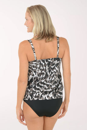 Woman wearing a black and white patterned tank top and black bottoms on a white background