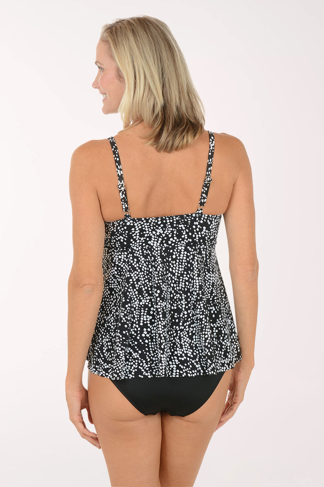 Woman wearing a black and white patterned tankini set on a white background. Back shot.