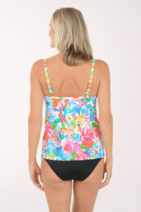 Woman wearing a colorful floral tank top and black shorts on a white background.  Back shot.