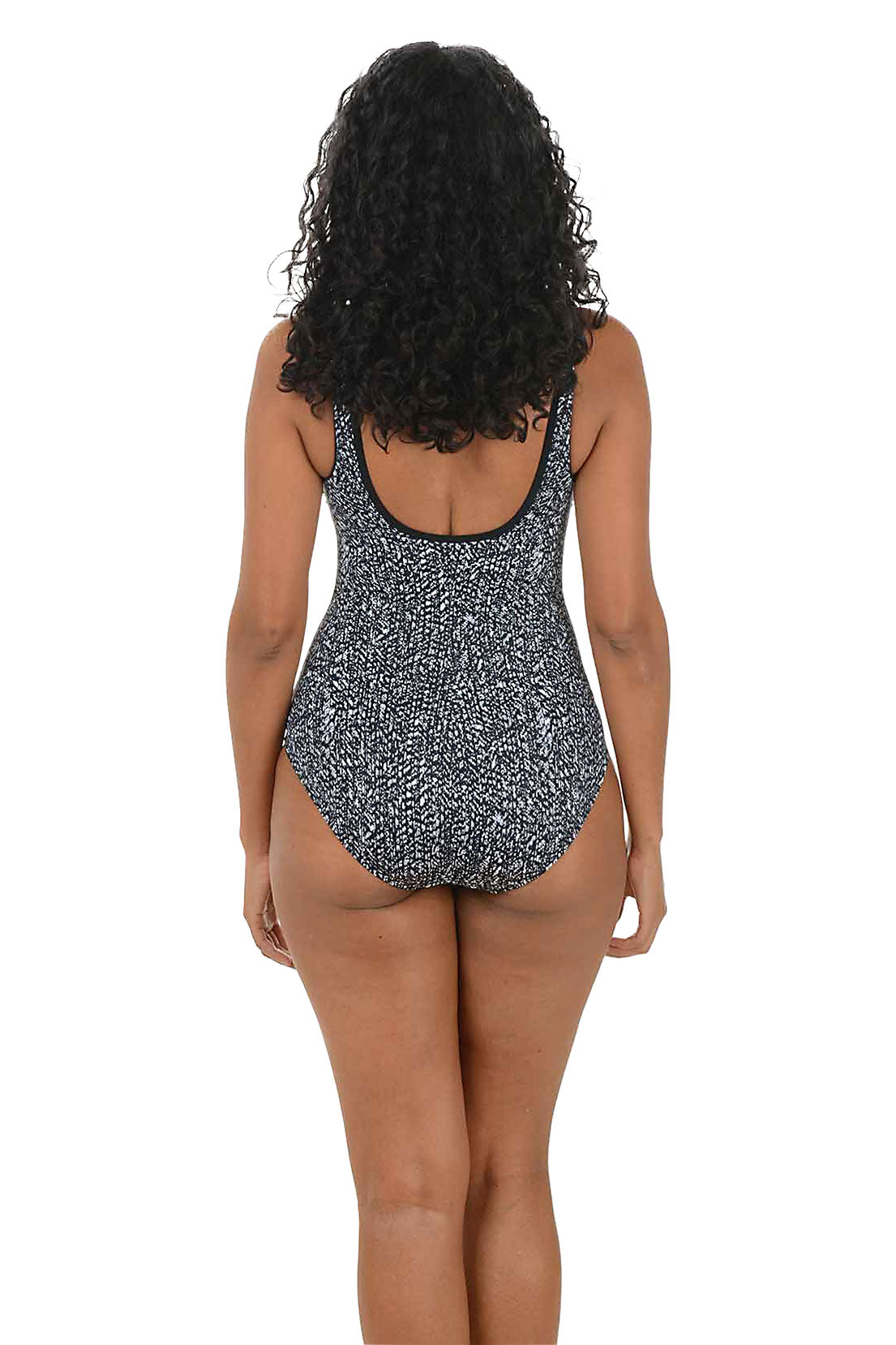 Woman wearing a black and white patterned swimsuit on a white background. Back shot.