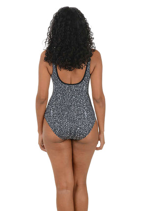 Woman wearing a black and white patterned swimsuit on a white background. Back shot.