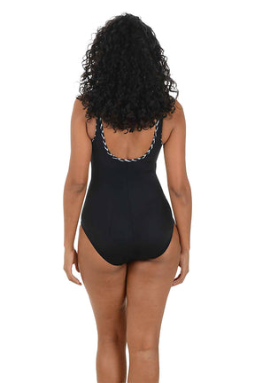 Woman wearing a black swimsuit with black and white decorative straps on a white background. Back shot.