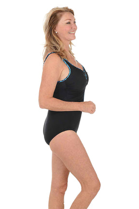 Woman wearing a black swimsuit with a turquoise piping on a white background. Side shot.