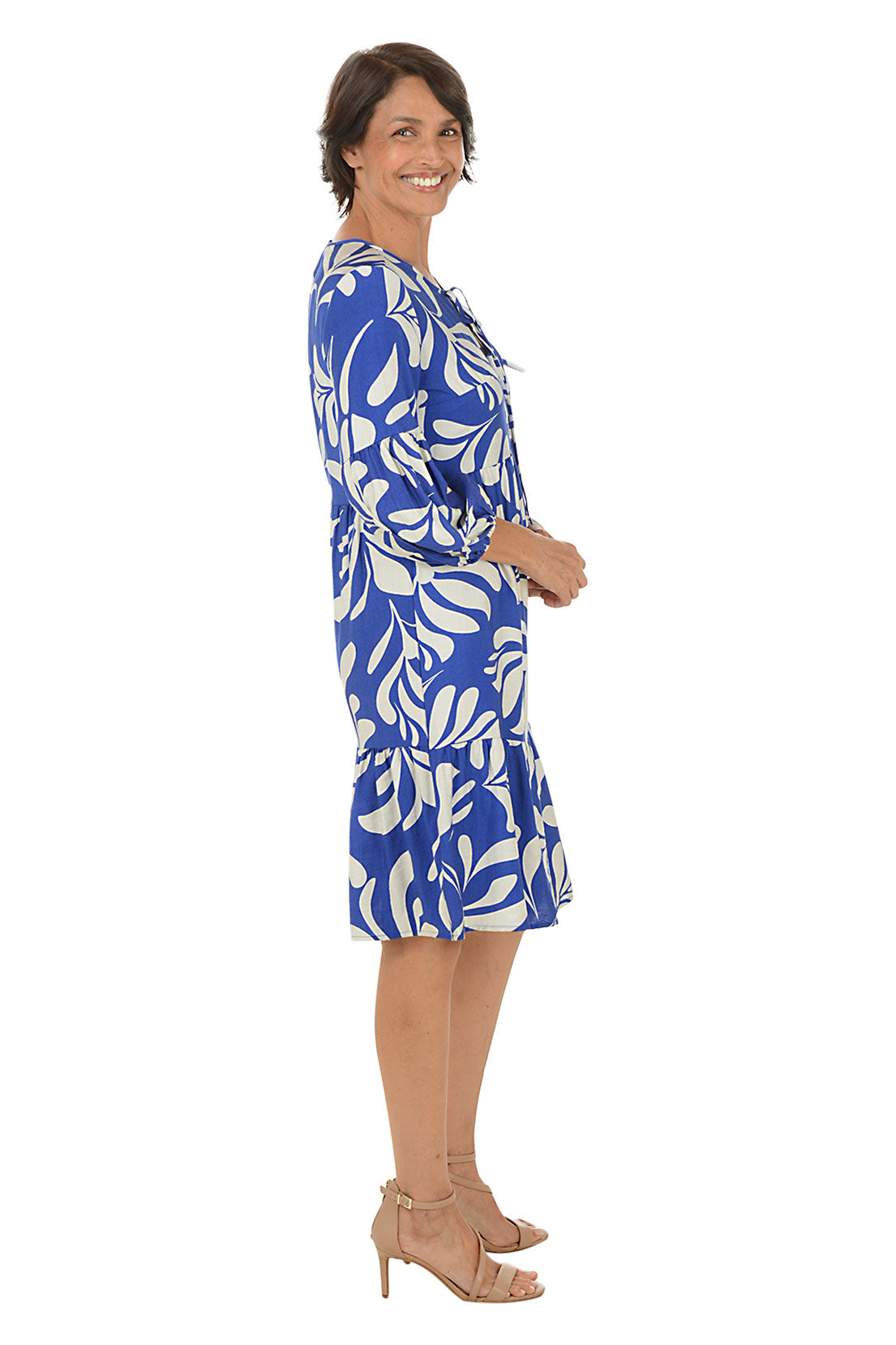 Woman wearing a blue and white patterned dress on a white background. Side shot.