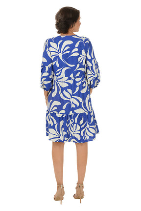 Woman wearing a blue and white patterned dress on a white background. Back shot.