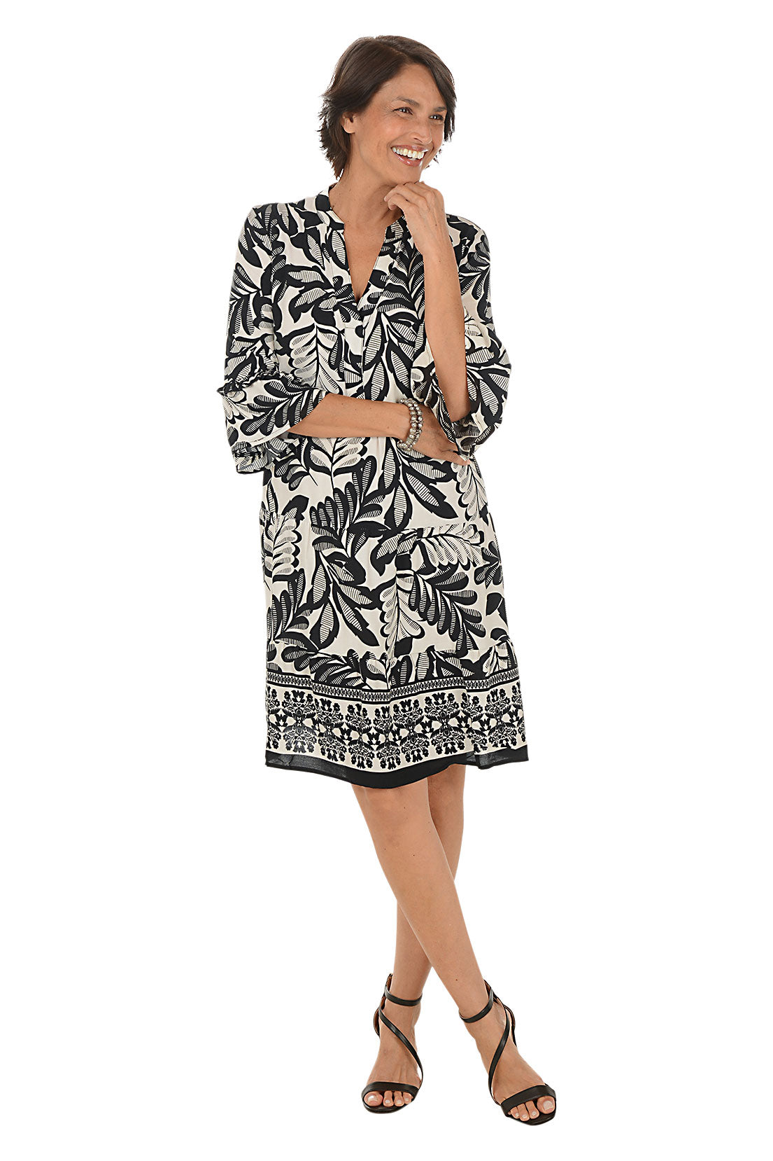 Woman wearing a black and white patterned dress on a white background. Second front shot.