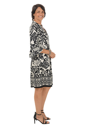 Woman wearing a black and white patterned dress on a white background. Side shot.