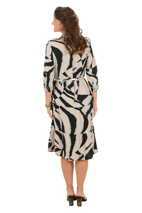 Woman wearing a black and brown patterned dress on a white background. Back shot.
