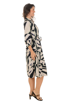 Woman wearing a black and brown patterned dress on a white background. Side shot.