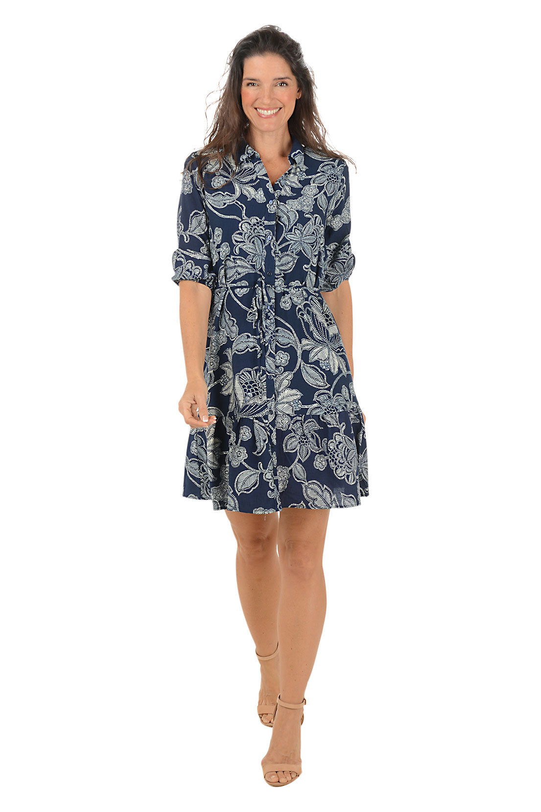 Woman wearing a 3/4 sleeve navy floral patterned dress with roll-up sleeves and a collar.