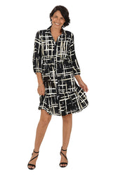 Woman wearing a black and white patterned dress on a white background. Second front shot.