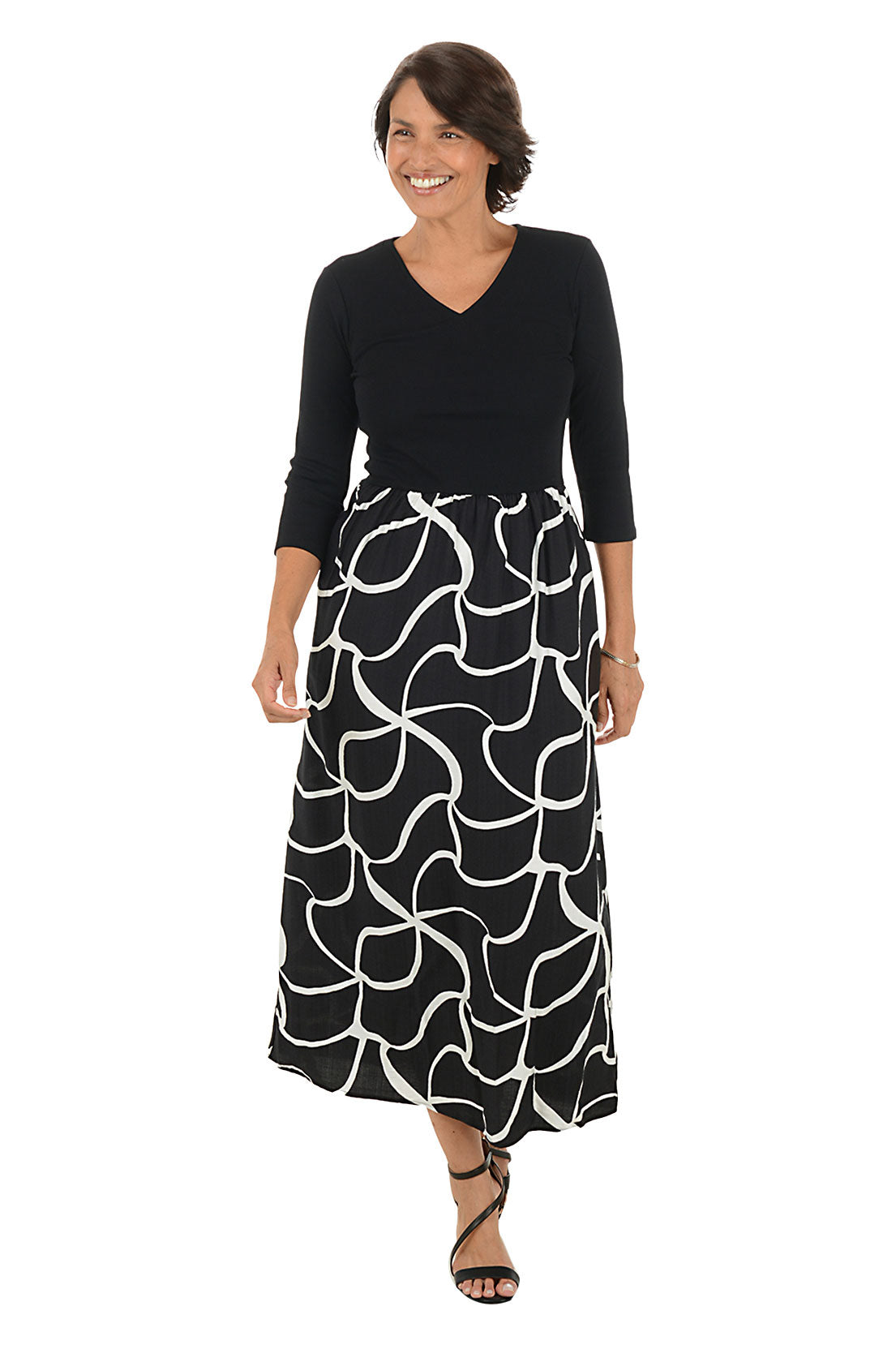 Woman wearing a 3/4 sleeve black and white patterned maxi dress on a white background. Side shot.