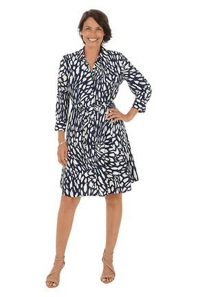 Woman wearing a navy and white patterned dress on a white background.