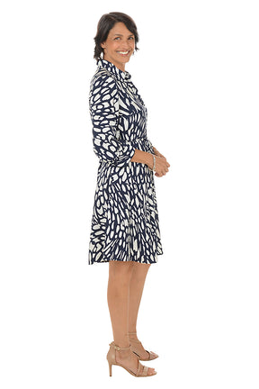 Woman wearing a navy and white patterned dress on a white background. Side shot.