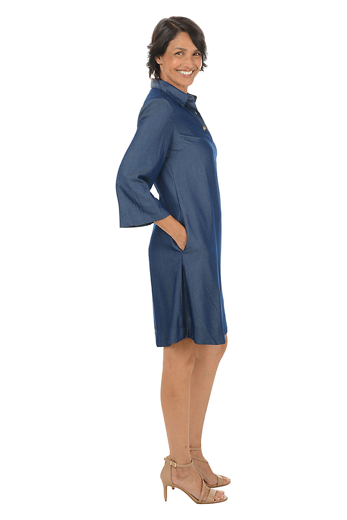Woman wearing a blue dress on a white background. Side shot.