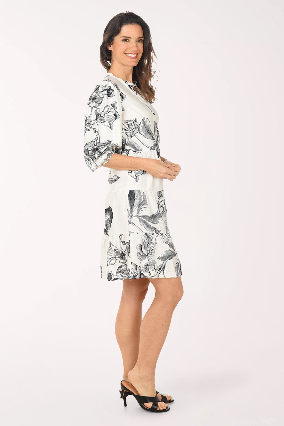 Woman wearing a white dress with black floral pattern on a white background
